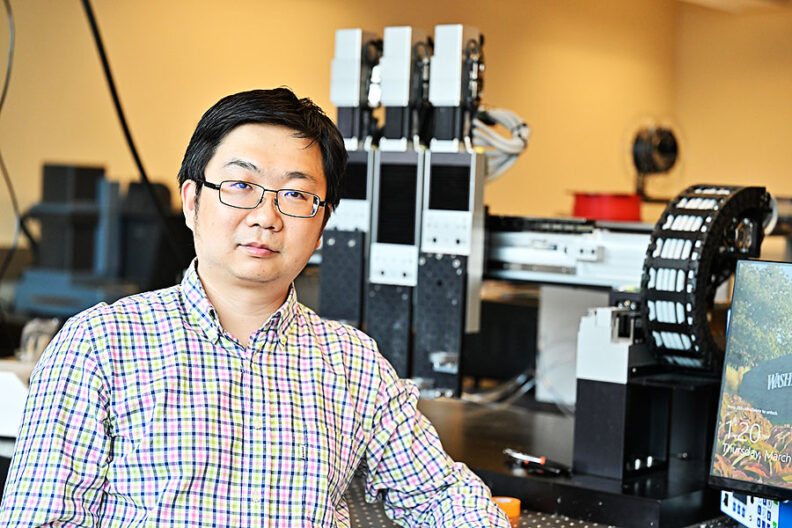 WSU engineer Kaiyan Qiu in his lab stands in front of 3D printers