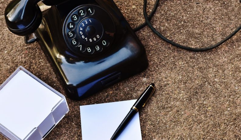 retro black phone with pen and paper
